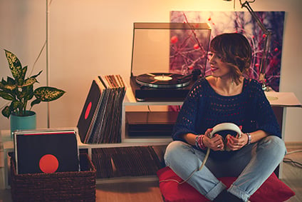 Woman listens to vinyl records sitting on the floor