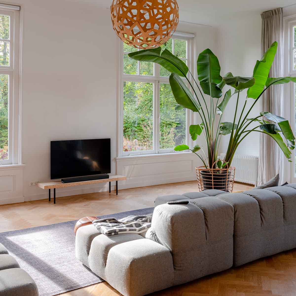 Harman Kardon Enchant 900 Soundbar lifestyle view with soundbar on table in front of TV