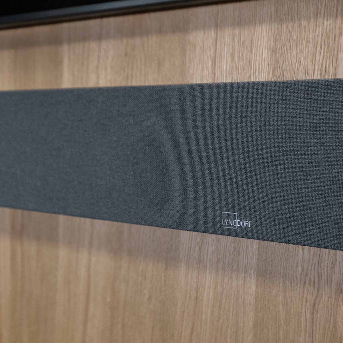 Lyngdorf SB-75 Passive Stereo Speaker Bar - lifesyle photo of unit mounted below TV closeup of Lyngdorf logo
