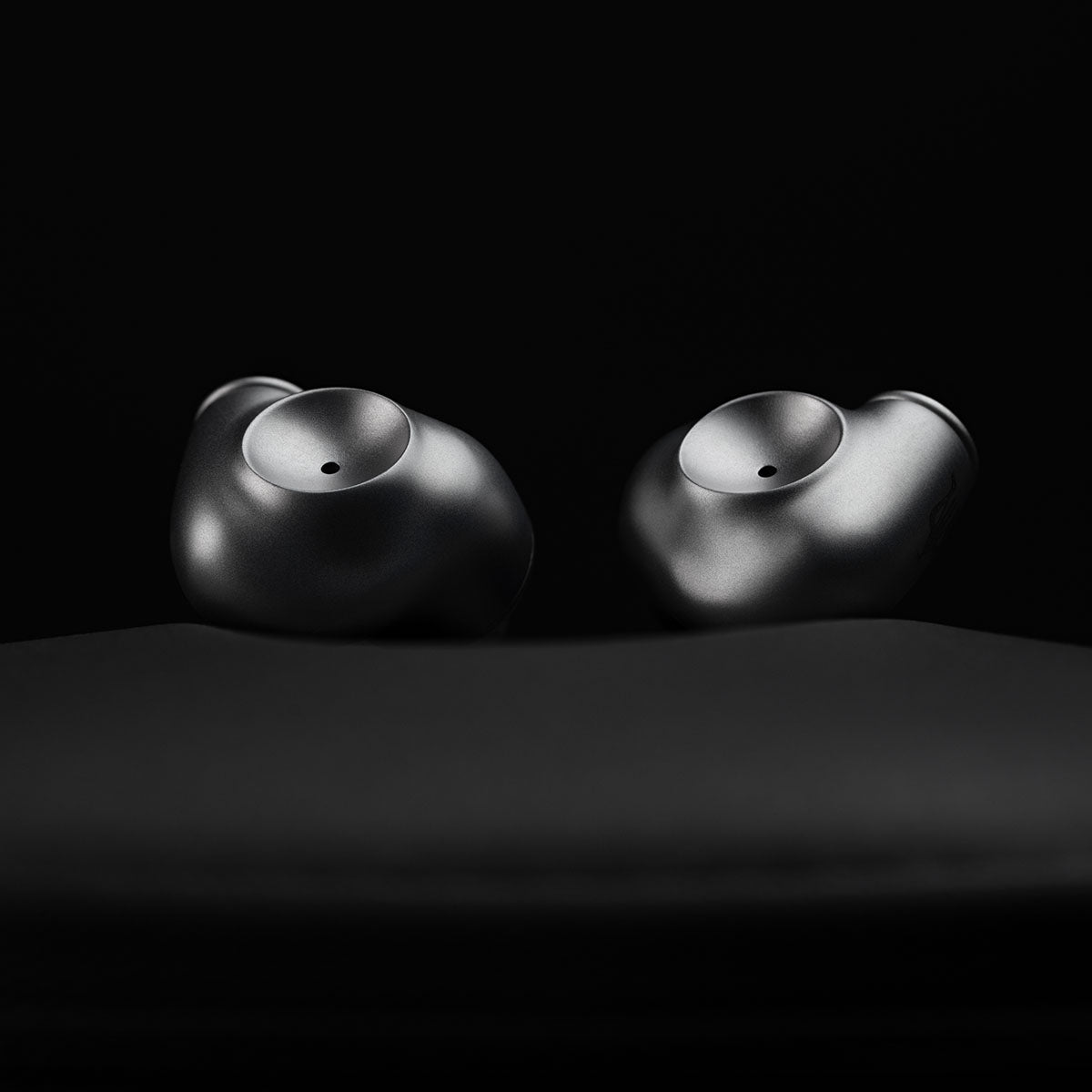 Meze Audio ASTRU Single Dynamic Driver In-Ear Monitors - artistic photo of both earbuds on black background