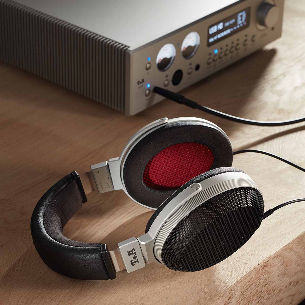 T+A Solitaire P High Performance Open-Back Planar Magnetostatic Headphones - lifestyle shot of unit connected to headphone amp laying on counter