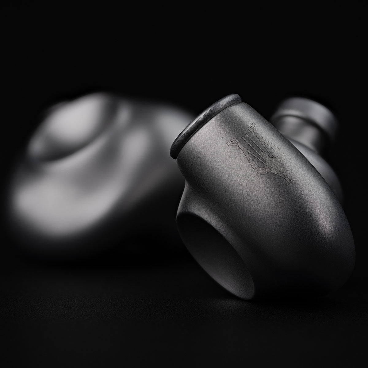 Meze Audio ASTRU Single Dynamic Driver In-Ear Monitors - artistic photo of both earbuds on black background, right earbud in focus showing Meze logo