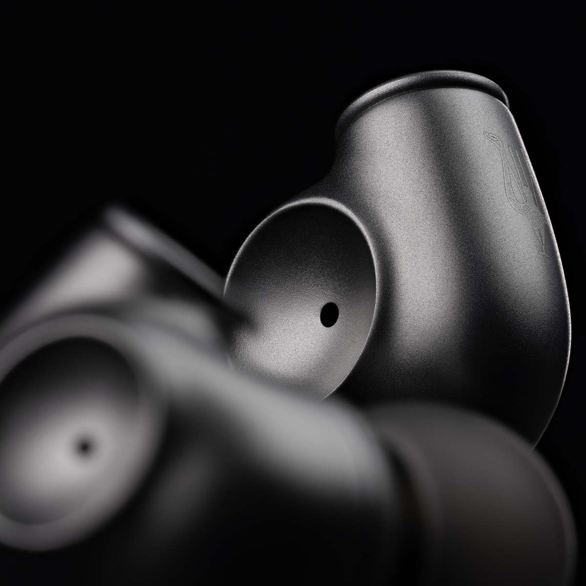 Meze Audio ASTRU Single Dynamic Driver In-Ear Monitors - artistic photo of both earbuds on black background, right earbud in focus showing Meze logo