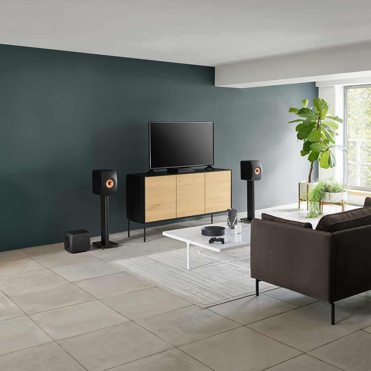 KEF KC62 Subwoofer - Carbon Black - sitting on floor in living room w/ LS50 on stands with TV between