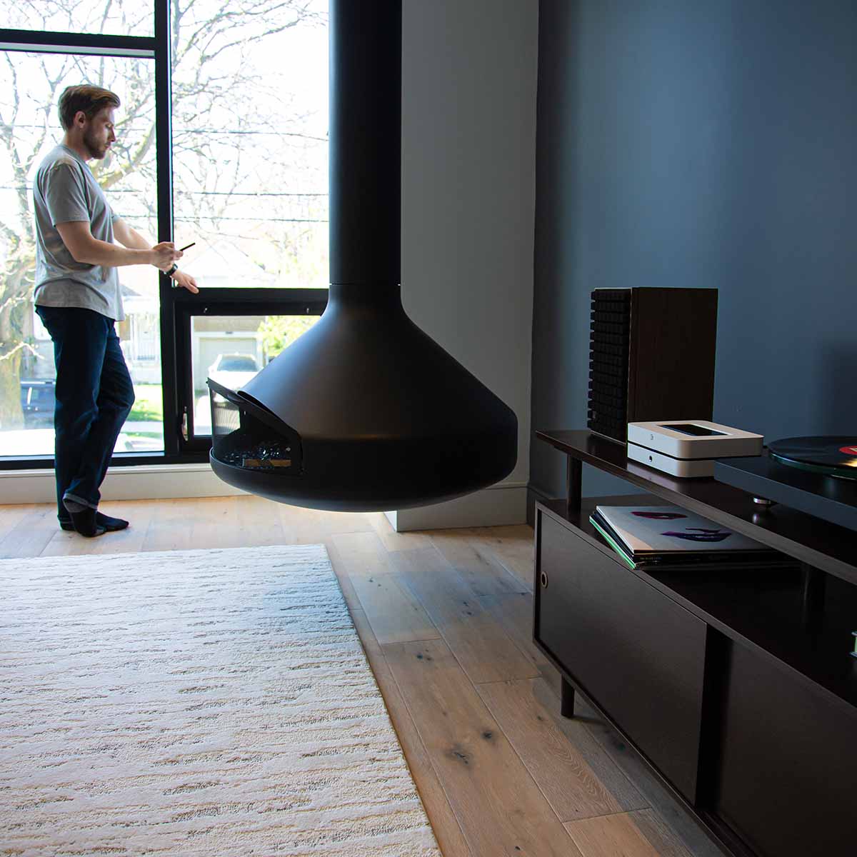 Bluesound POWERNODE N331 Multi-Room Streaming Amplifier - white - lifestyle photo of unit on cabinet to right with fireplace and man in background