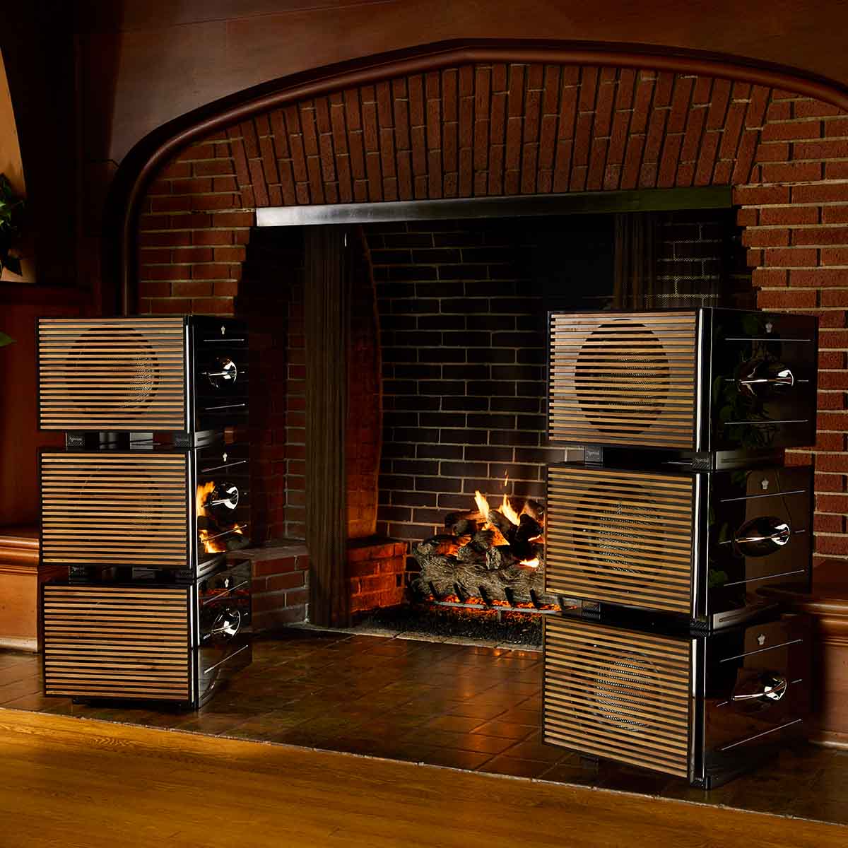 REL Acoustics Carbon Special Black Label Subwoofer lifestyle shot 2 stacks of three units with grilles on either side of fireplace