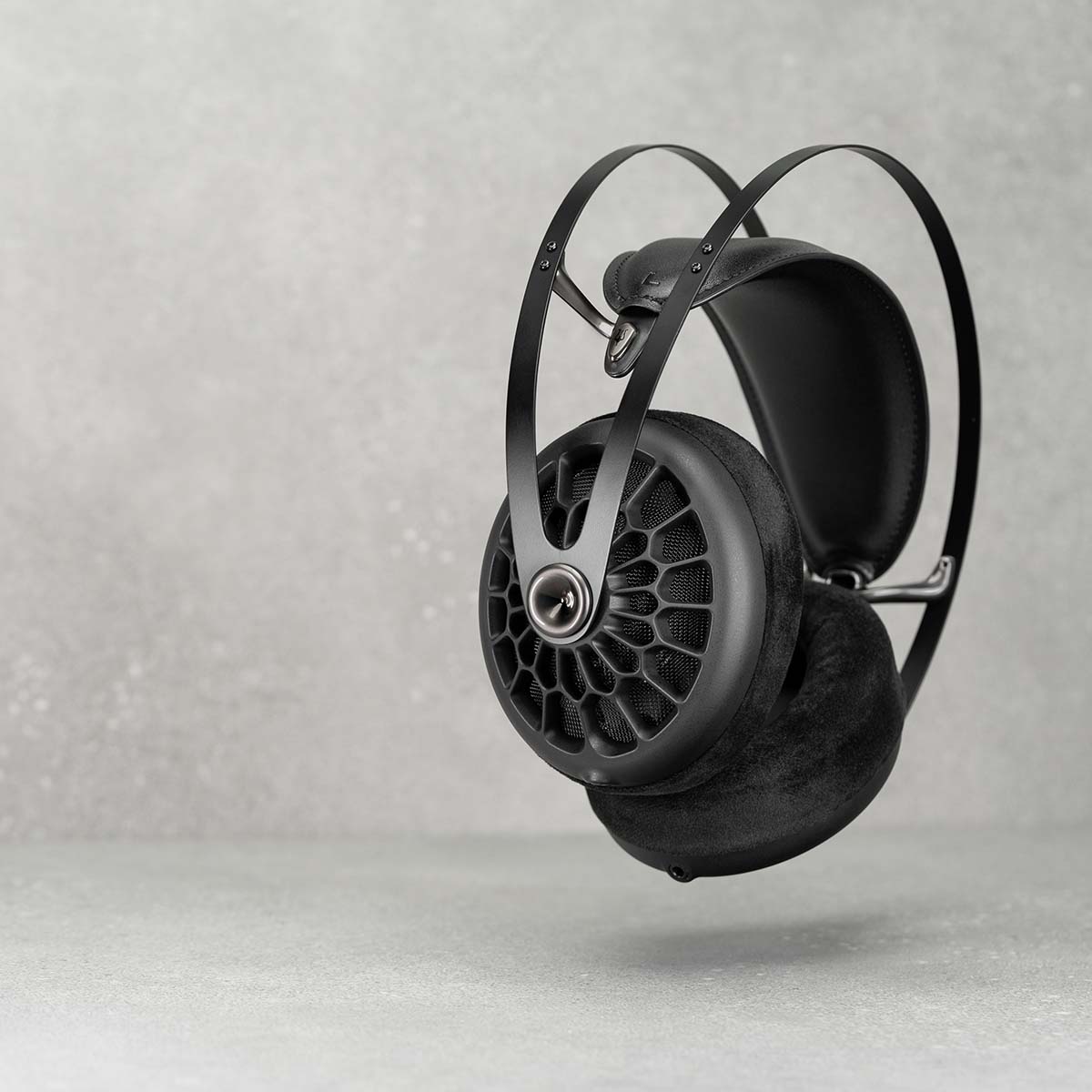 Meze 105 AER Open-Back Headphones - black floating with stone background left earphone forward
