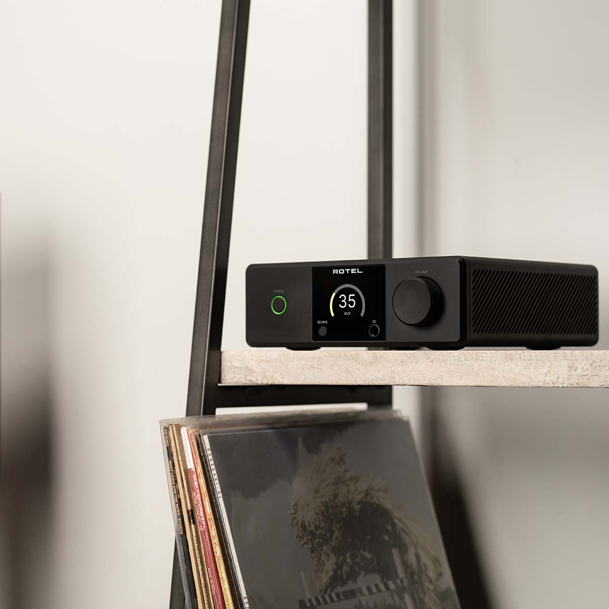 Lifestyle photo Rotel DX-5 Integrated Amplifier - black front view facing left on shelf with records below