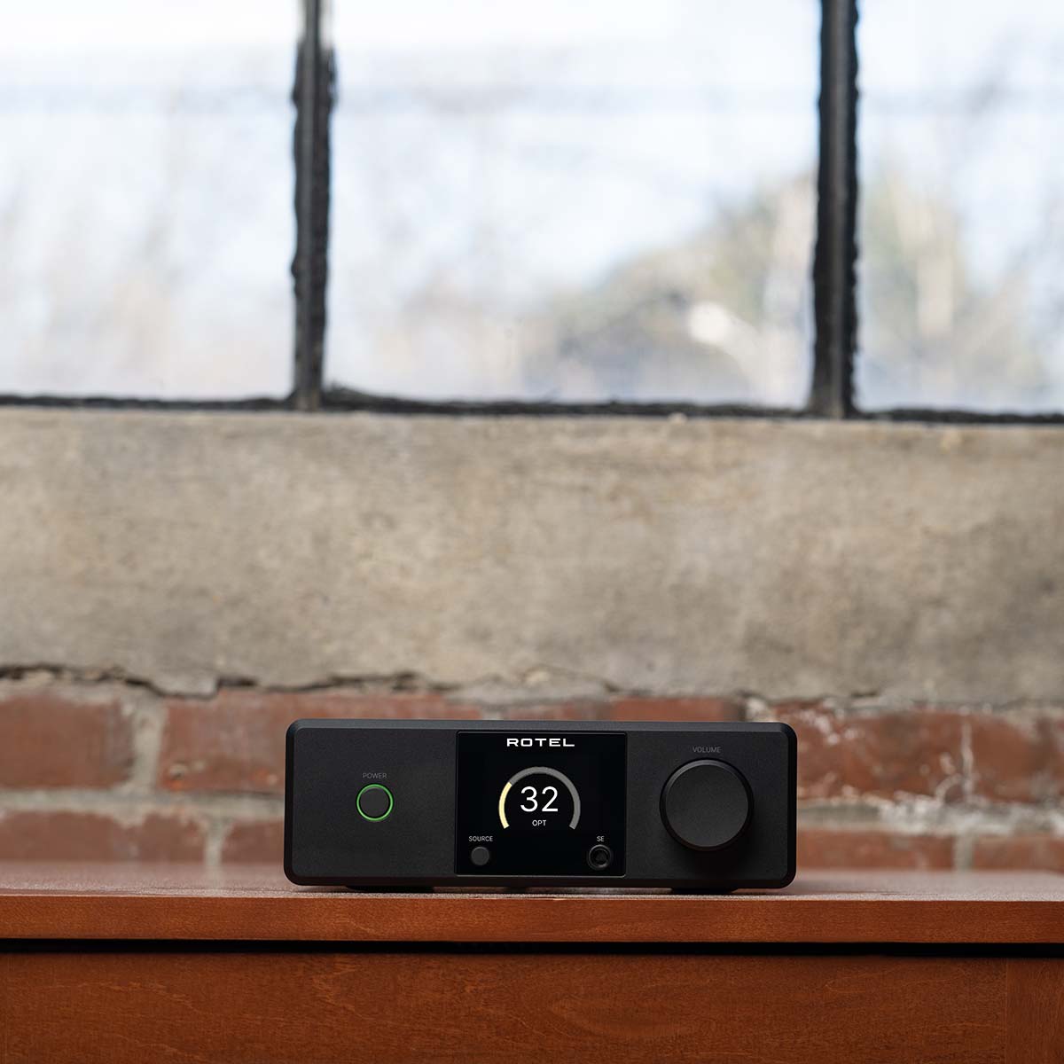 Lifestyle photo Rotel DX-5 Integrated Amplifier - black front view in front ov brick wall with windows