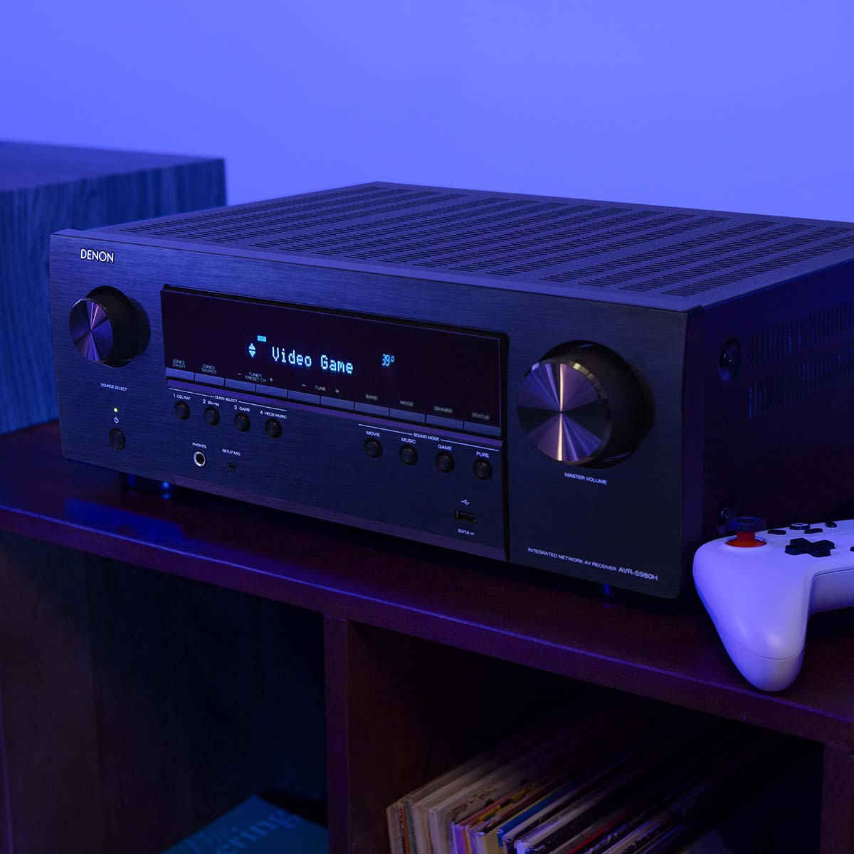 Denon AVR-S980H AV Receiver lifestyle photo of unit on cabinet set to Video Game mode with controller to right
