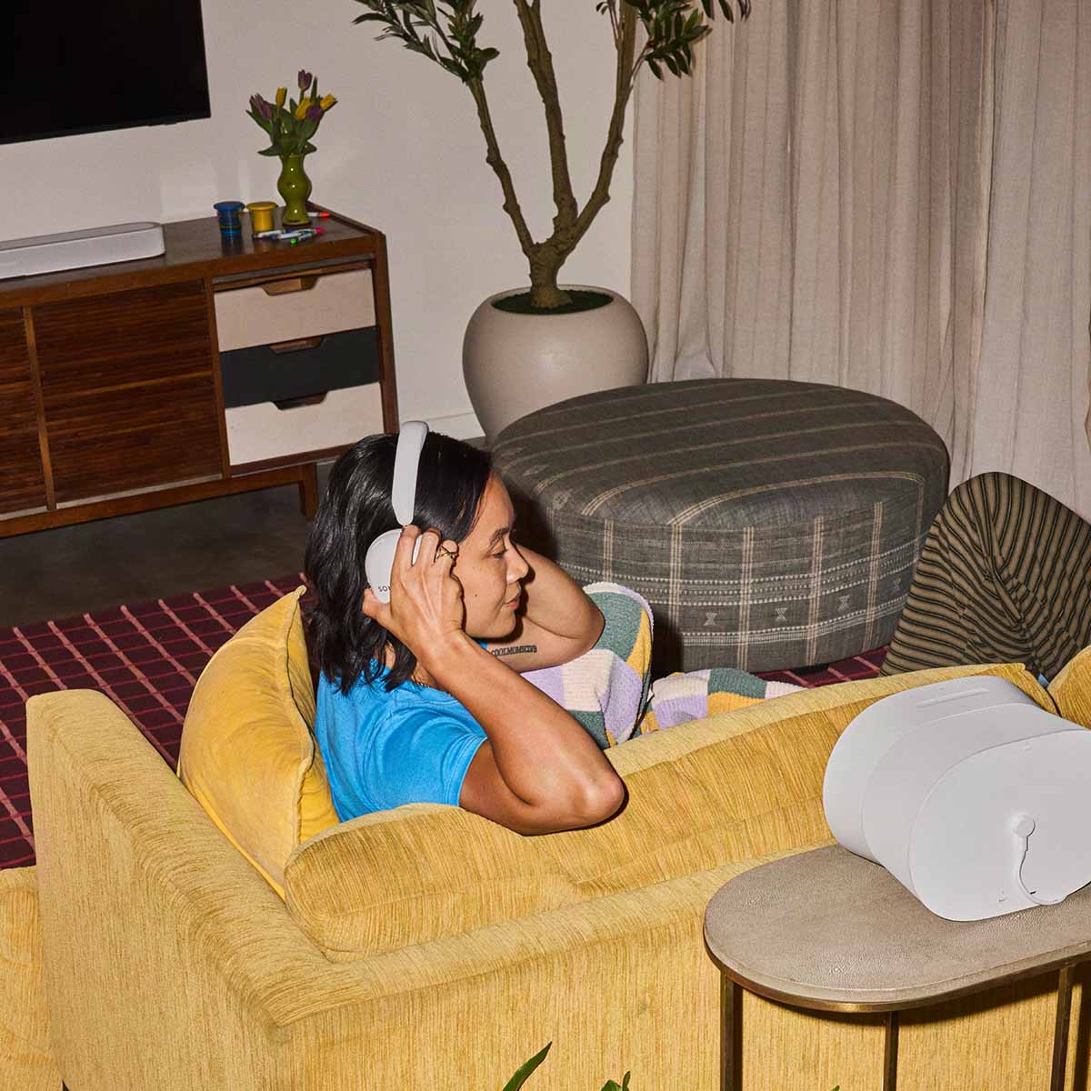 Sonos Ace Ultra Wireless Over-Ear Headphones - lifestyle photo of a woman wearing white headphones sitting on a couch