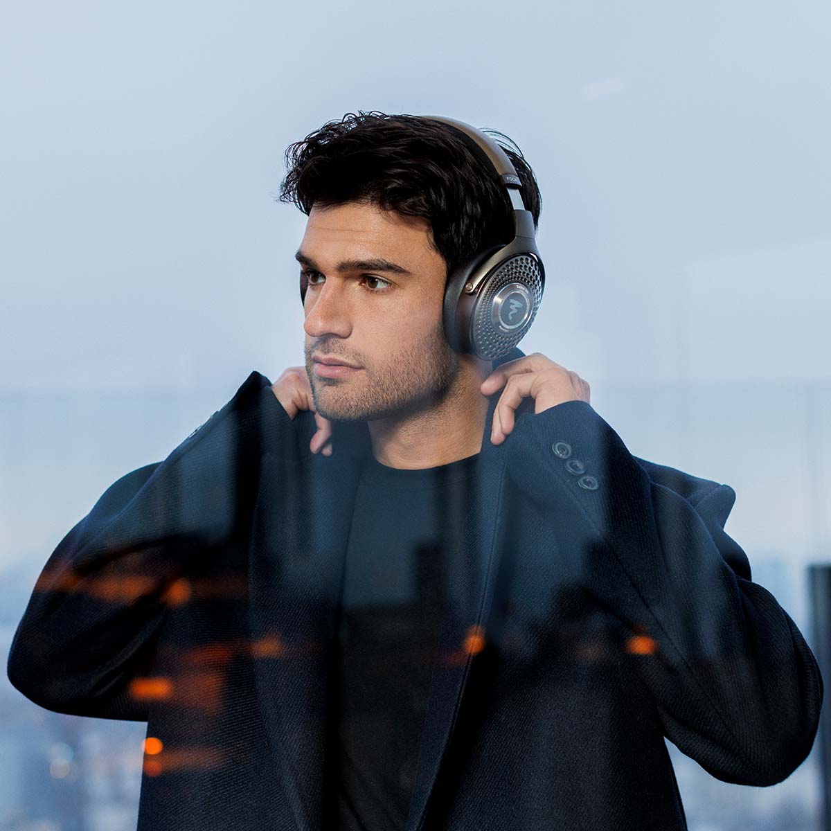 Focal Bathys MG Wireless Over-Ear Active Noise Cancelling Headphones - lifestyle shot man wearing headphones adjusting coat