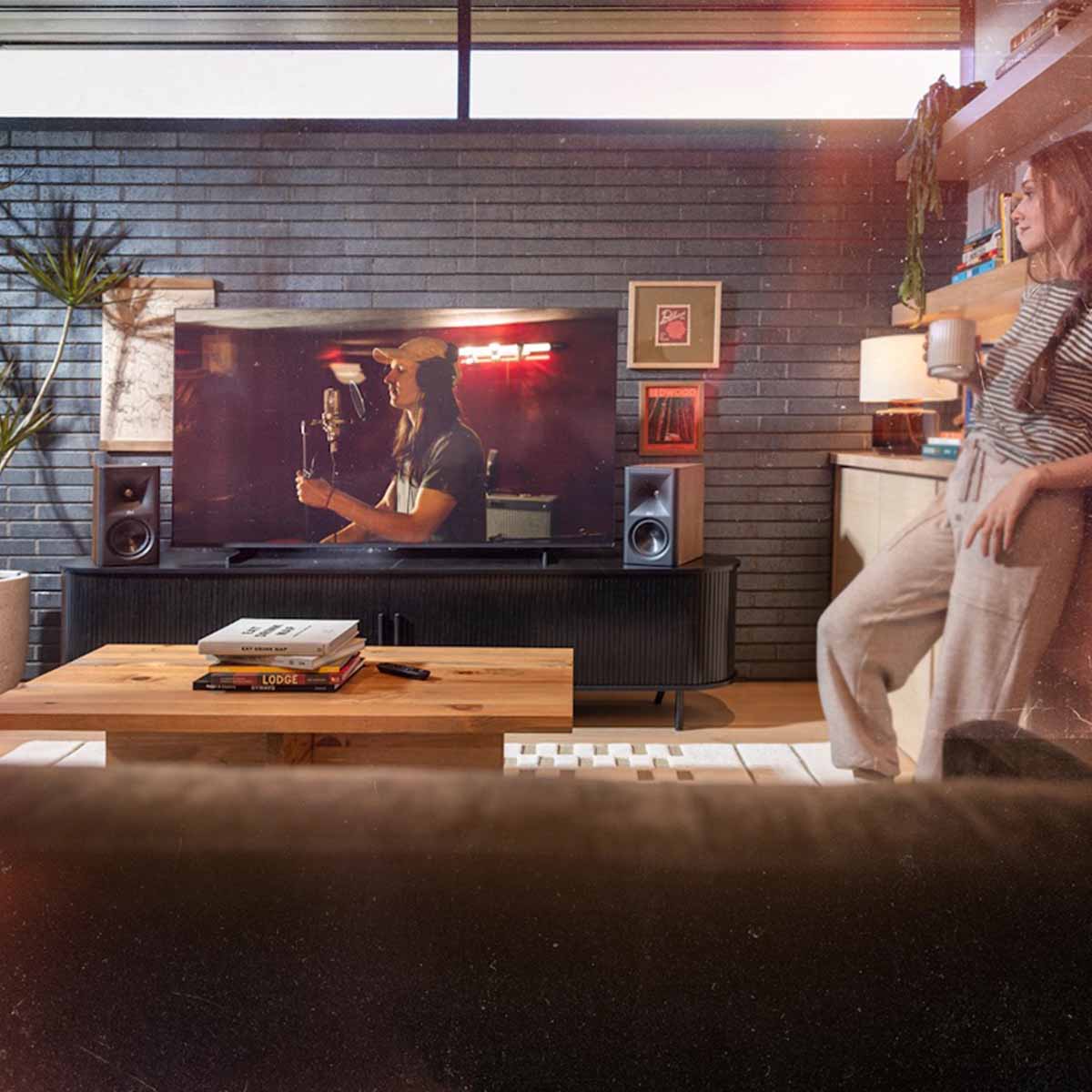 Klipsch The Fives II Dolby Atmos 5.25" Powered Speakers - Pair - lifestyle photo pair of walnut speakers on cabinet with woman to right of room
