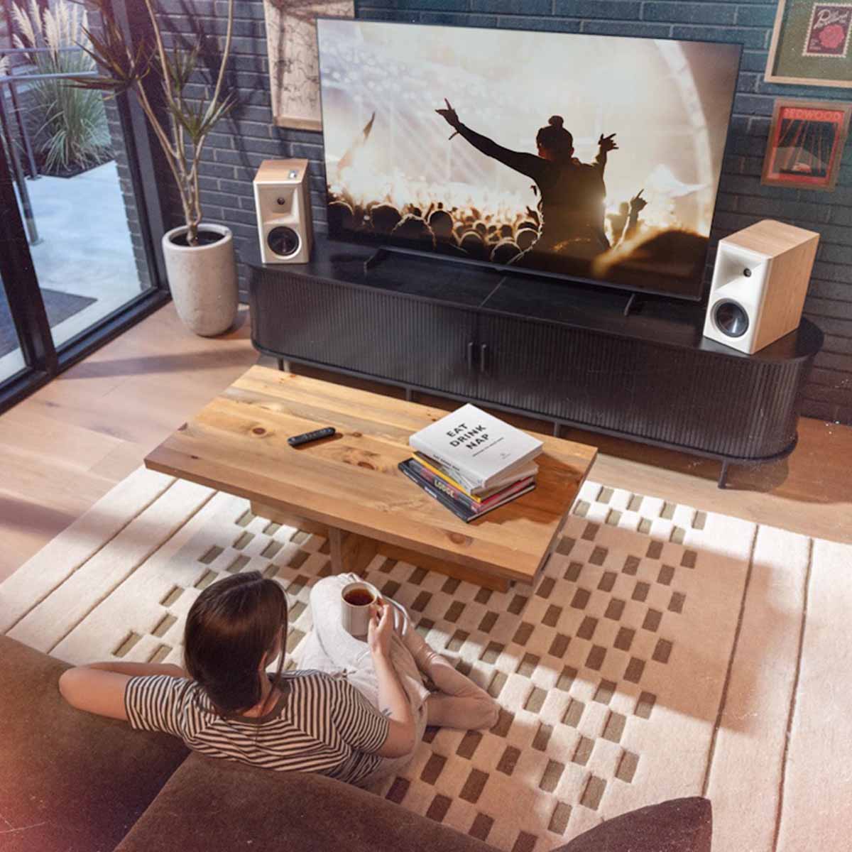 Klipsch The Fives II Dolby Atmos 5.25" Powered Speakers - Pair - lifestyle photo pair of red oak speakers on cabinet with woman seated on couch