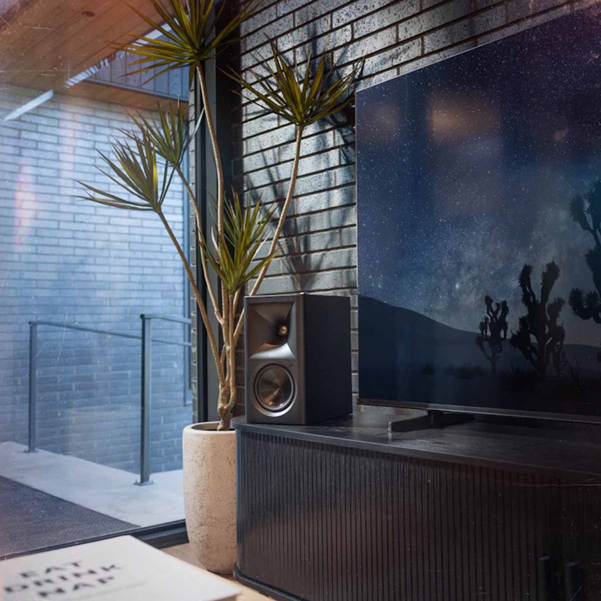 Klipsch The Fives II Dolby Atmos 5.25" Powered Speakers - single speaker - lifestyle photo single ebony speaker on cabinet with tv to right