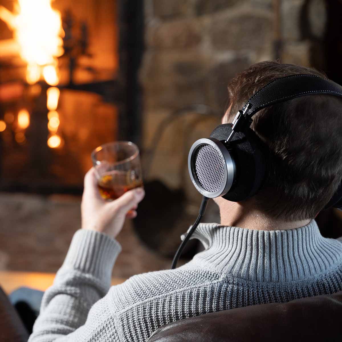 Grado Signature HP100 SE Headphones lifestyle shot man wearing headphones with whiskey glass facing away three-quarter view