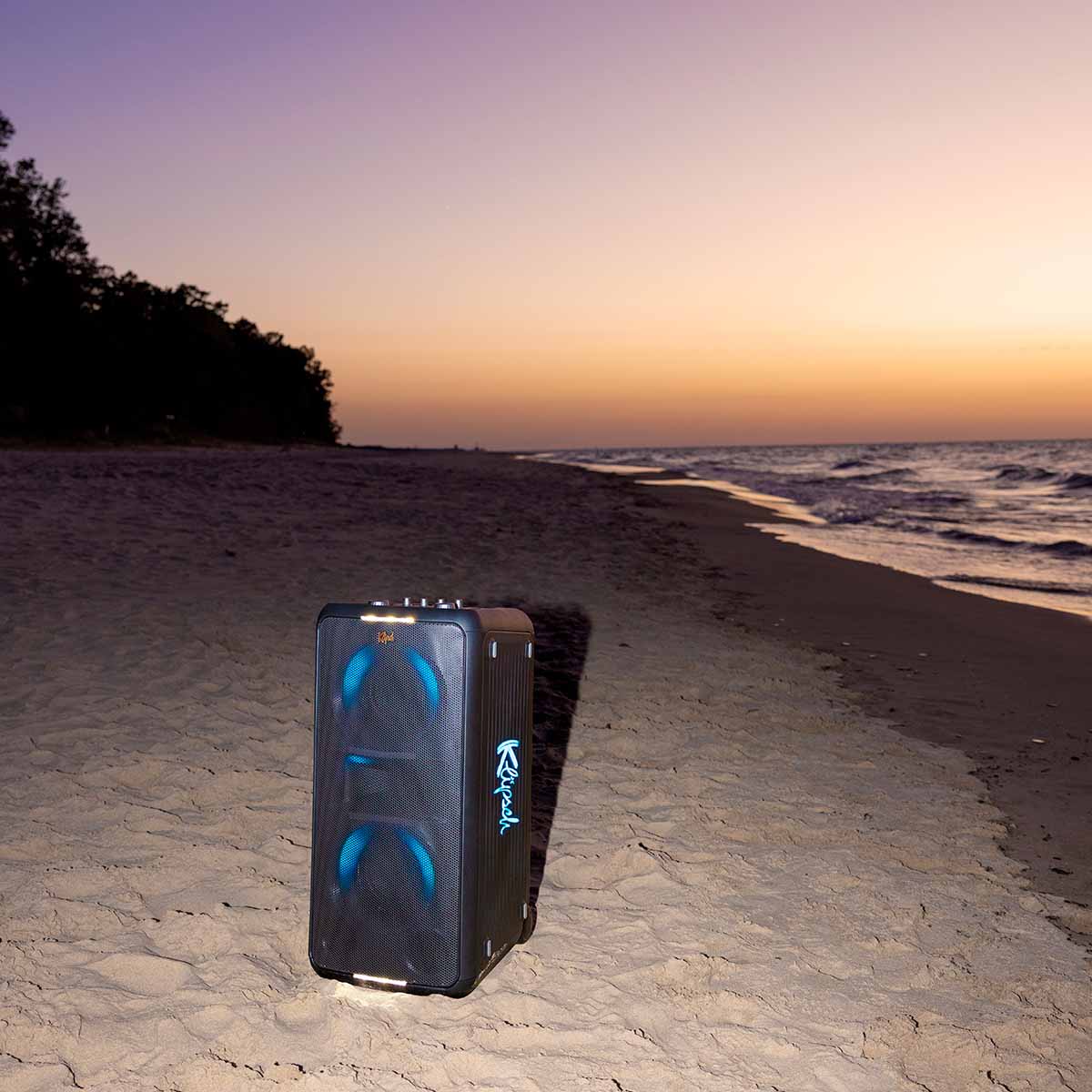 Klipsch Miami Music City Series Premium Party Speaker lifestyle shot with speaker on the beach at sunset front and side view angled left with blue lights