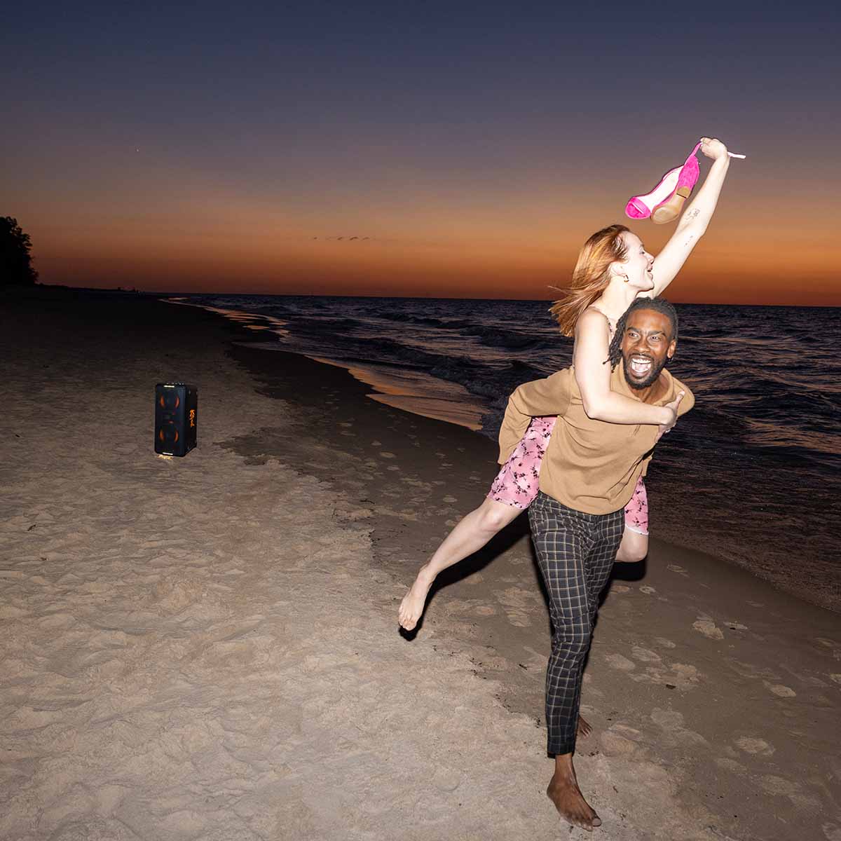 Klipsch Miami Music City Series Premium Party Speaker lifestyle shot with speaker in background front and side view angled left with orange lights