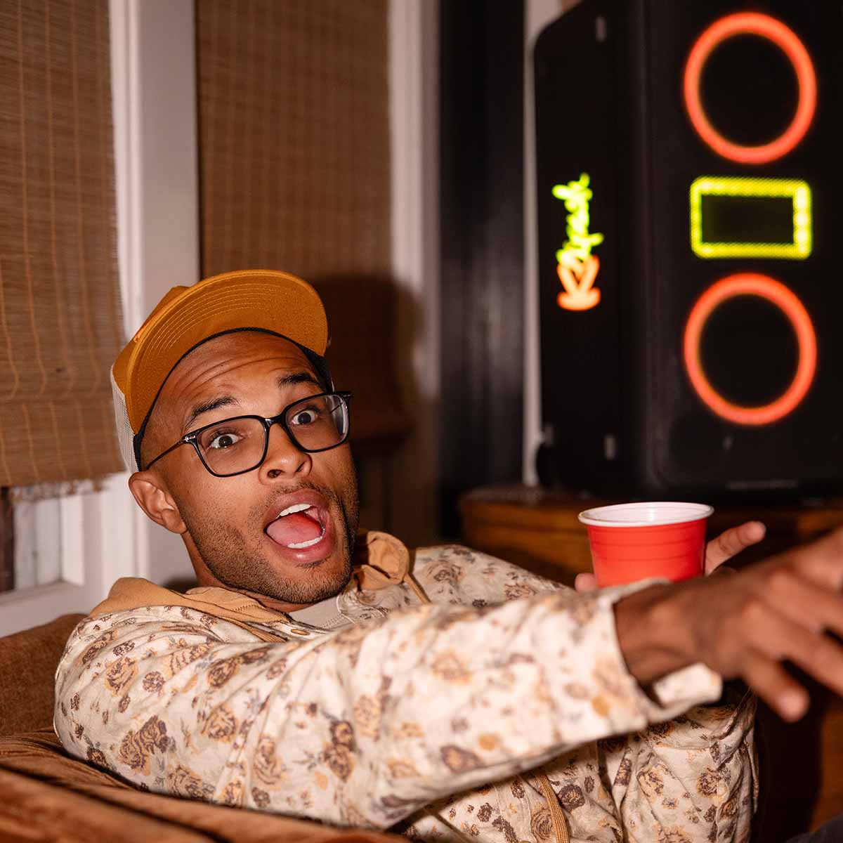 Klipsch Miami Music City Series Premium Party Speaker lifestyle shot with speaker in background front and side view angled right with orange and yellow lights