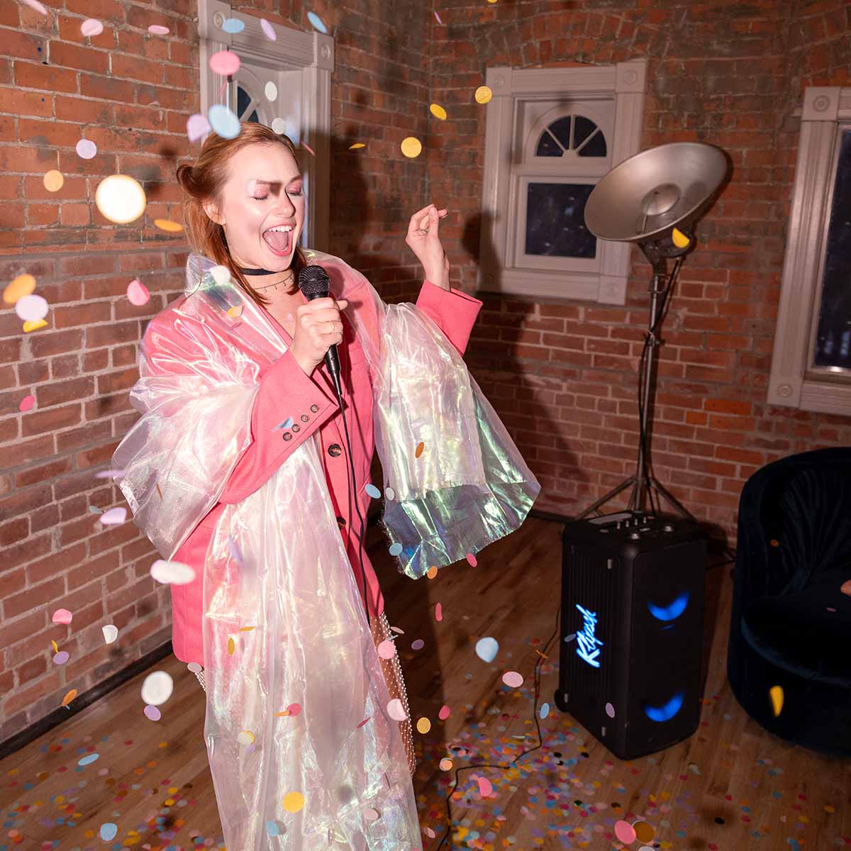 Klipsch Miami Music City Series Premium Party Speaker lifestyle shot with speaker in background front and side view angled right with blue lights