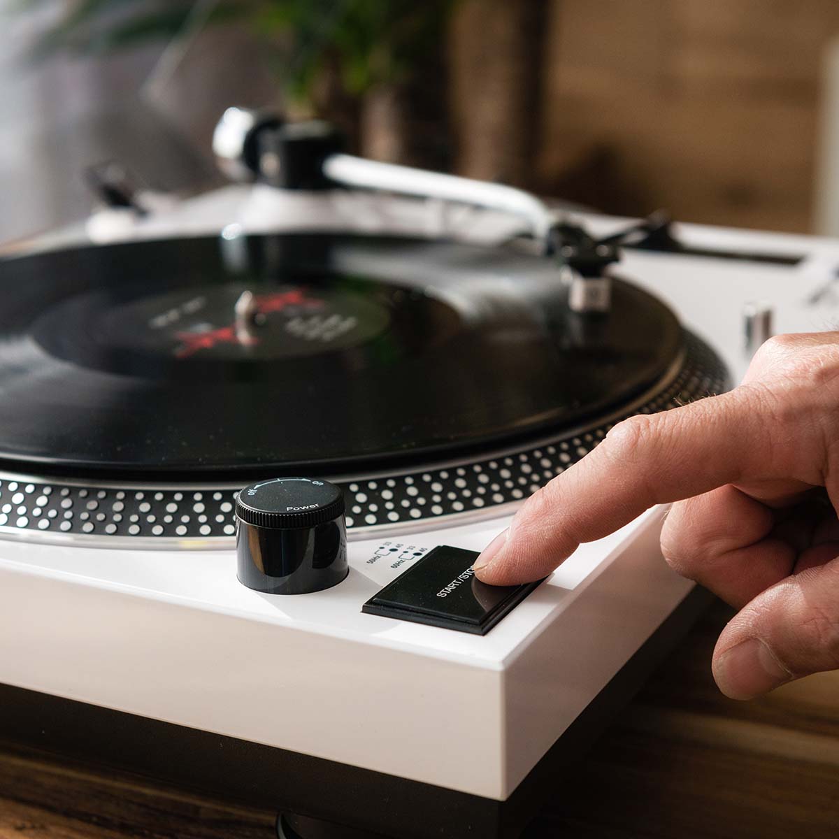 Lenco L-3810 Direct-Drive Turntable w/ Pinch Control - White Lifestyle shot closeup of left side of unit with hand pressing start/stop button