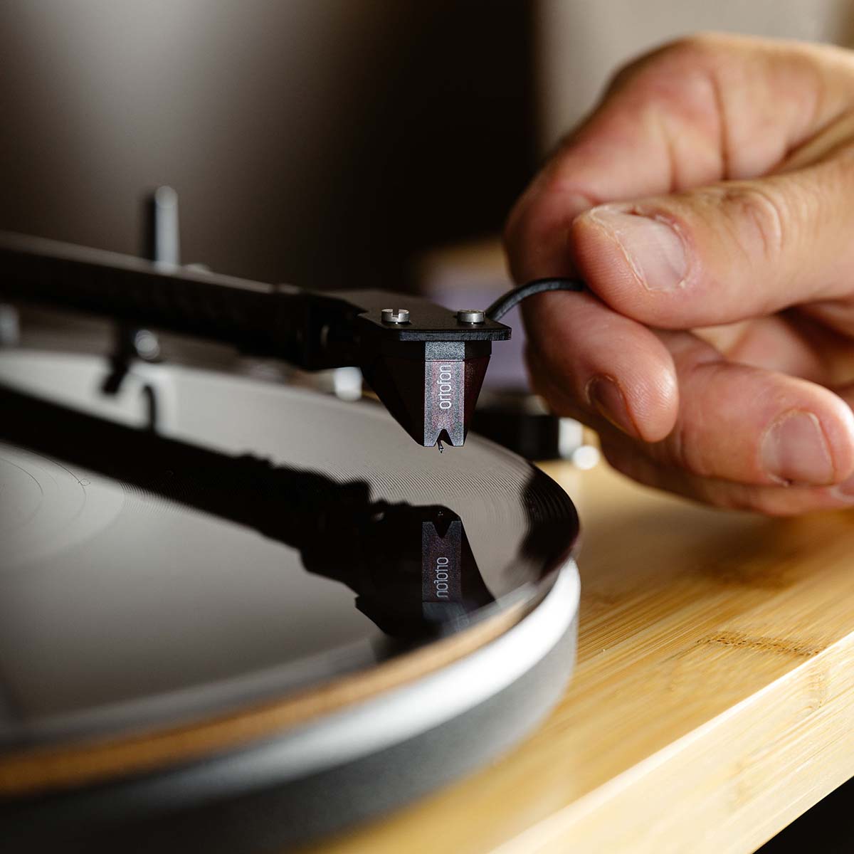 Lenco LBT-335 Bluetooth Turntable w/ Ortofon 2M Red Cartridge lifestyle photo closeup of hand and placing tonearm on record focus on cartridge