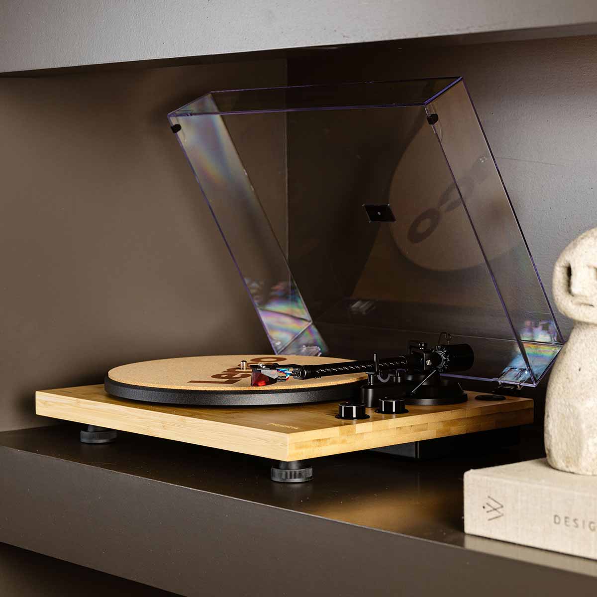 Lenco LBT-335 Bluetooth Turntable w/ Ortofon 2M Red Cartridge lifestyle photo unit on shelf showing right side of unit angled left showing tonearm and control knobs with cork mat on platter and open dustcover