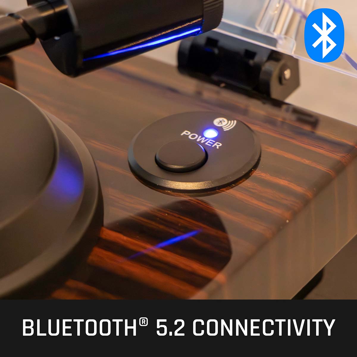 Lenco LBT-345 Bluetooth Turntable w/ Ortofon 2M Red lifestyle shot angled down and left with open dustcover close-up of engaged power button with bluetooth light on with text on bottom and Bluetooth logo in top right
