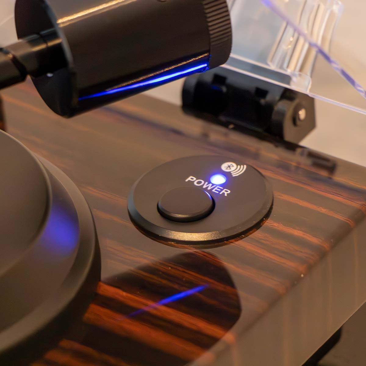 Lenco LBT-345 Bluetooth Turntable w/ Ortofon 2M Red lifestyle shot angled down and left with open dustcover close-up of engaged power button with bluetooth light on