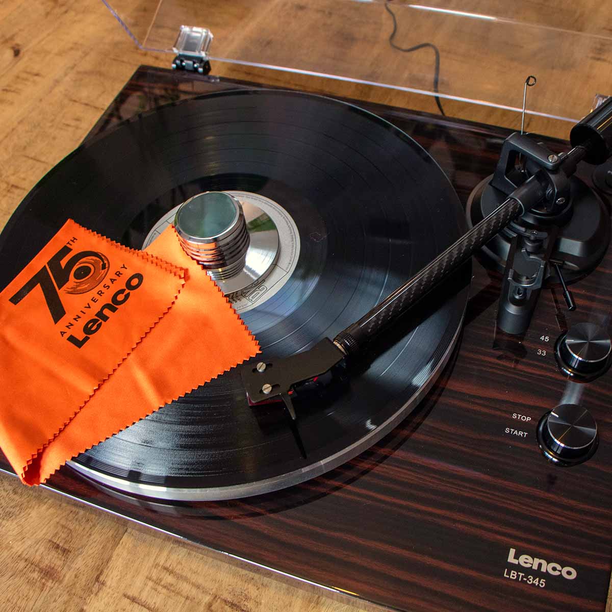 Lenco LBT-345 Bluetooth Turntable w/ Ortofon 2M Red lifestyle shot angled down and left with open dustcover and record on platter with tonearm engaged and record weight and Lenco branded cleaning cloth on record