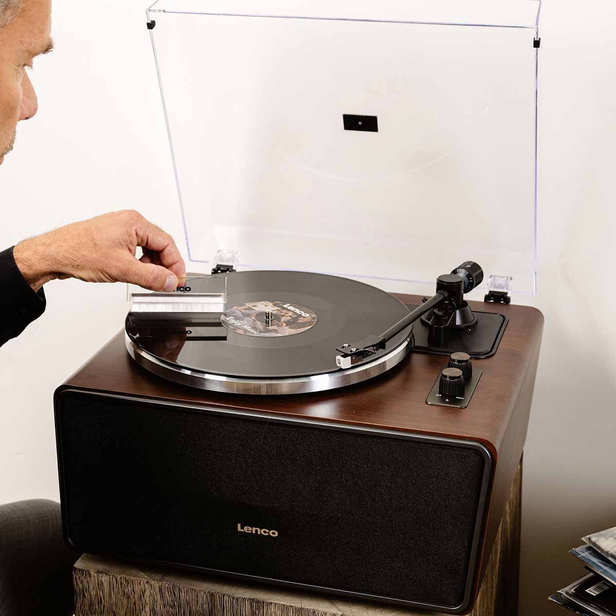 Lenco LS-470 Turntable w/ 80W Speaker System and Bluetooth lifestyle shot front view angled down with record on platter and man cleaning record with record brush