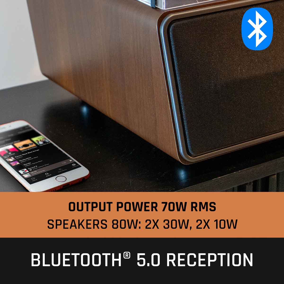 Lenco LS-470 Turntable w/ 80W Speaker System and Bluetooth front view angled right showing left side of front speaker with an iphone to left of unit, bluetooth logo in top right of image and text to bottom of image