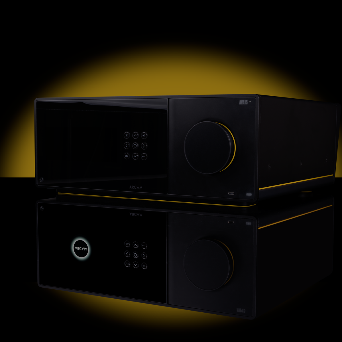 A black audio amplifier or receiver device with a glossy finish, featuring a digital keypad on the left and a large rotary volume control on the right, shown on a reflective black surface with a yellow glow behind it.