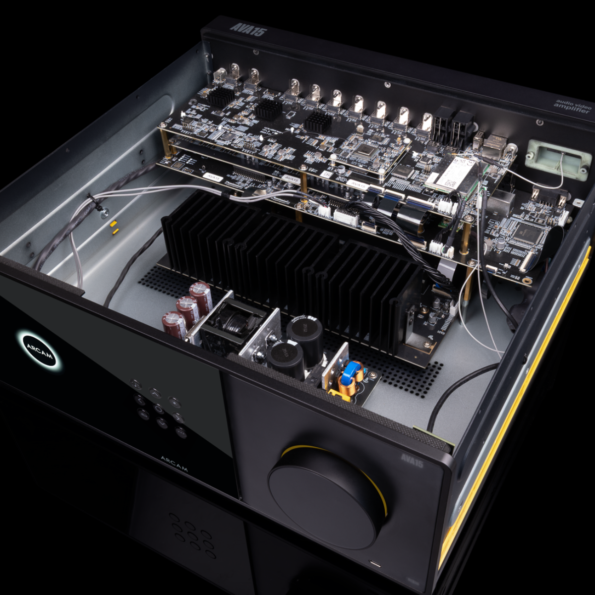 An open-front Arcam Radia AVA15 9-channel Class D Home Theater Receiver photographed at an angle on a black background, showing internal electronics, a large black heatsink, capacitors, and a front control panel with a dial.
