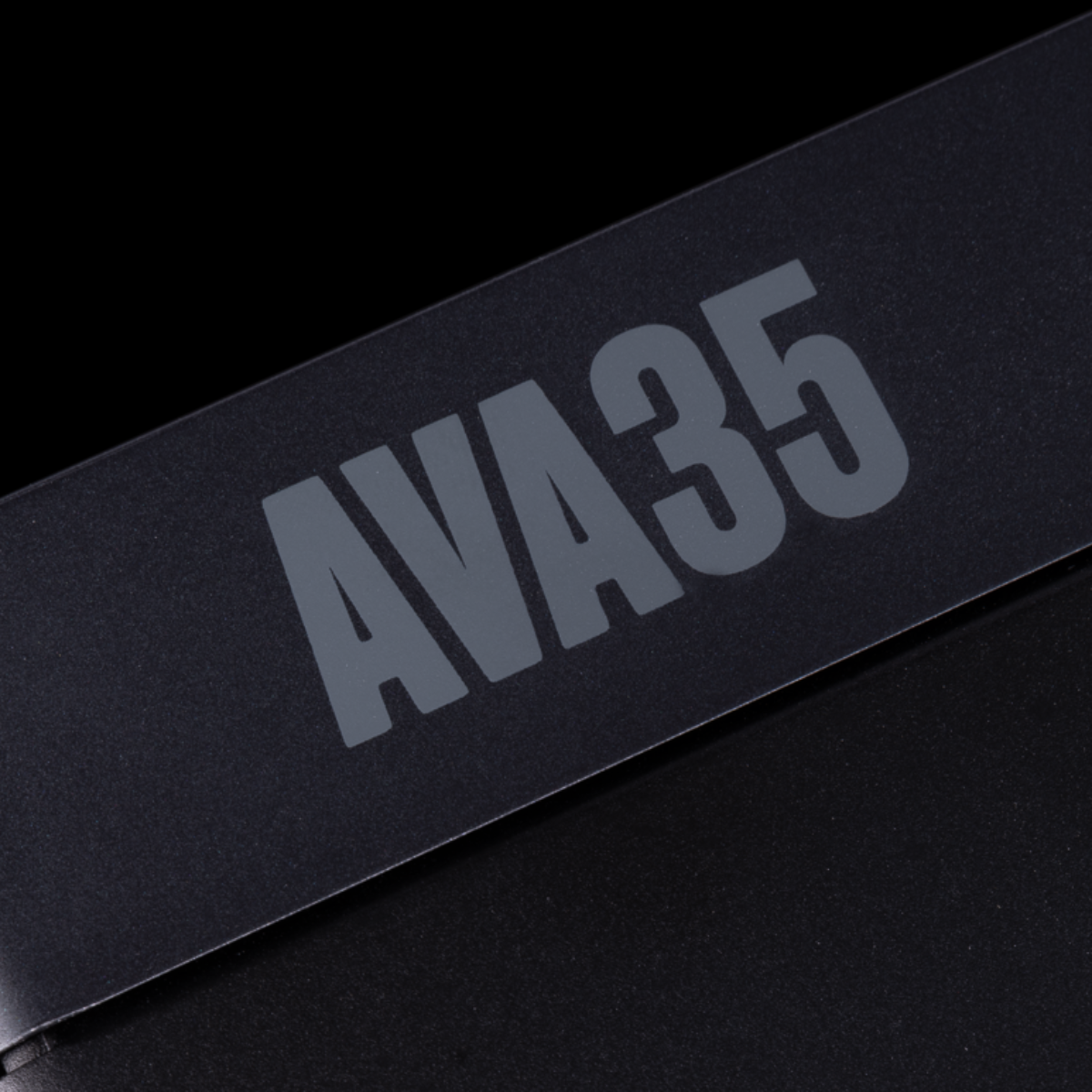 Close-up of a matte black rectangular product with large gray 'AVA35' lettering on a black background.