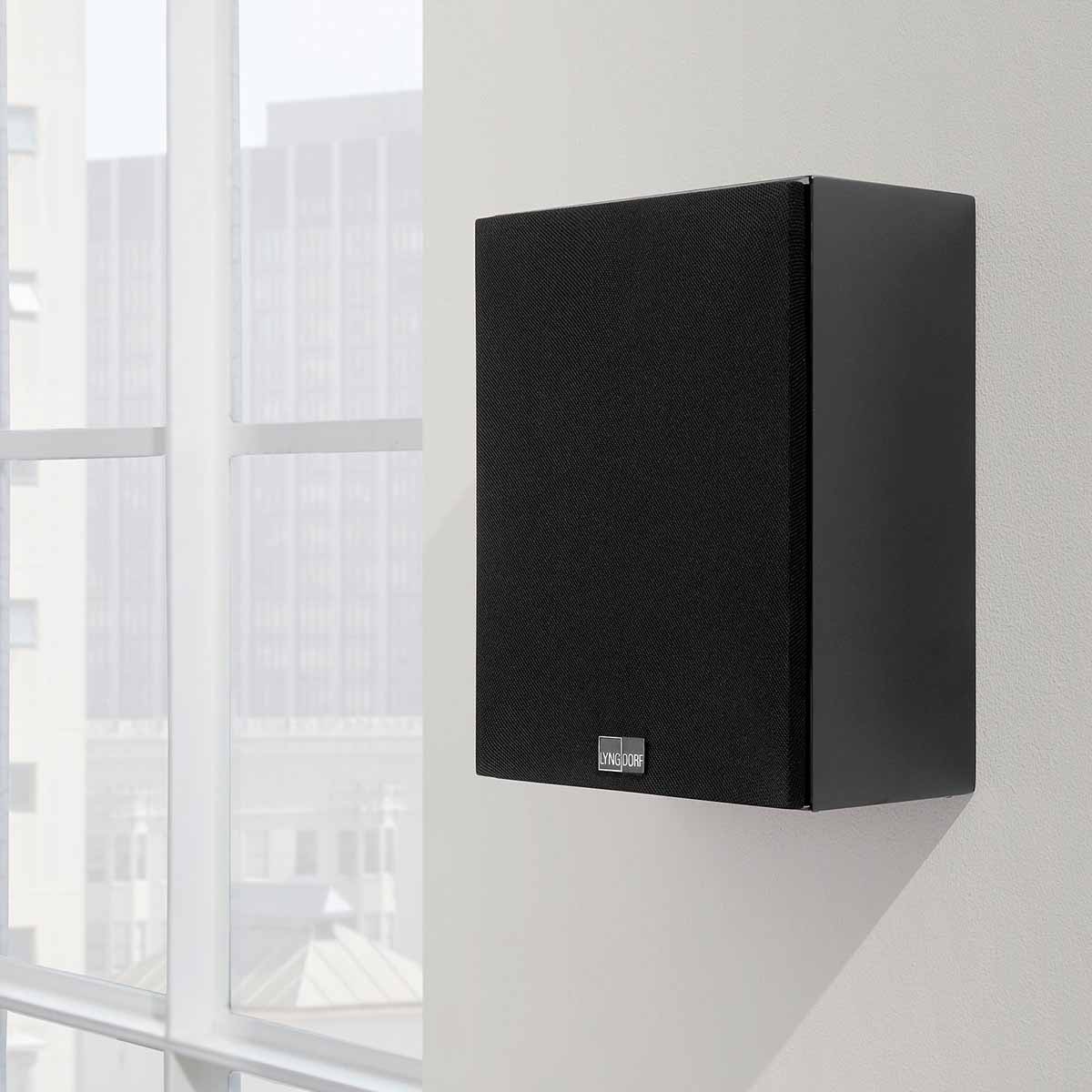 Lyngdorf MH-2 Satellite Speaker lifestyle shot black speaker with black grille mounted on wall