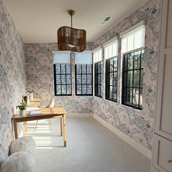 Room with floral wallpaper, wooden table, and large windows.