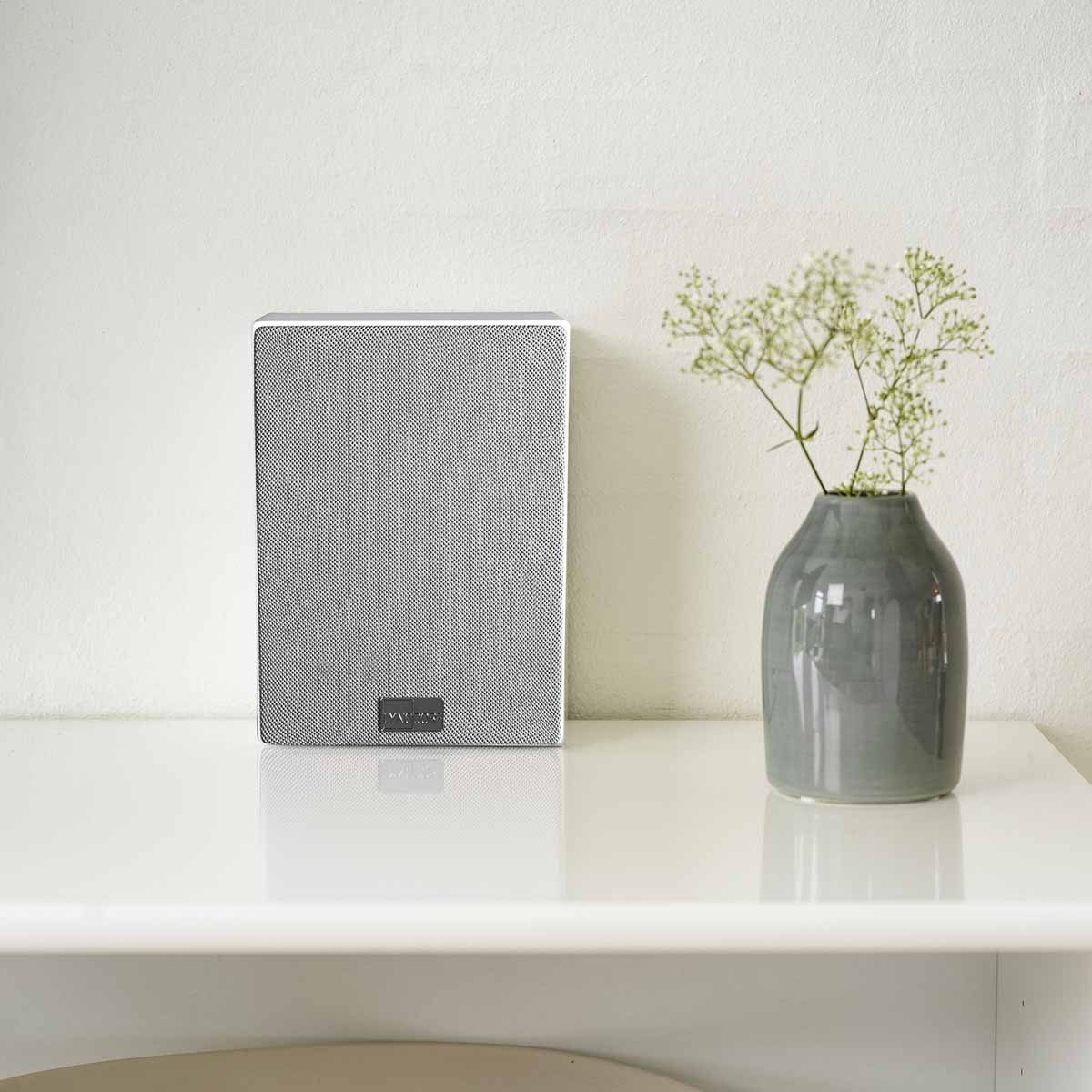 Lyngdorf MH-3 white Satellite Speaker front view lifestyle shot with pastel gray grille