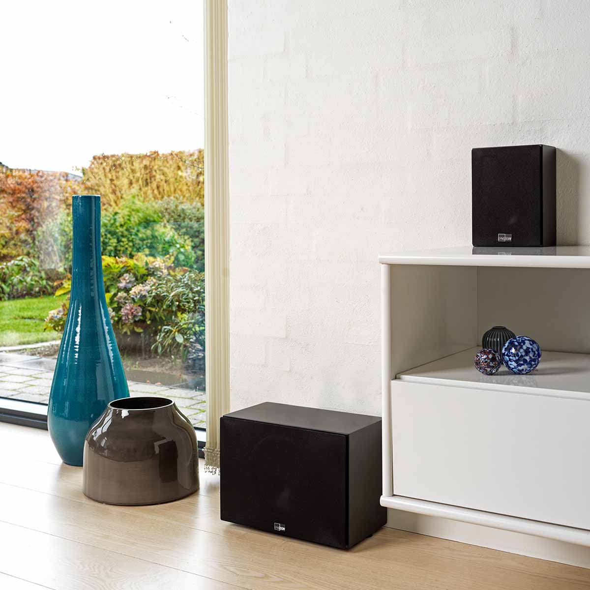 Lyngdorf MH-3 Black Satellite Speaker lifestyle photo with grille on shelf