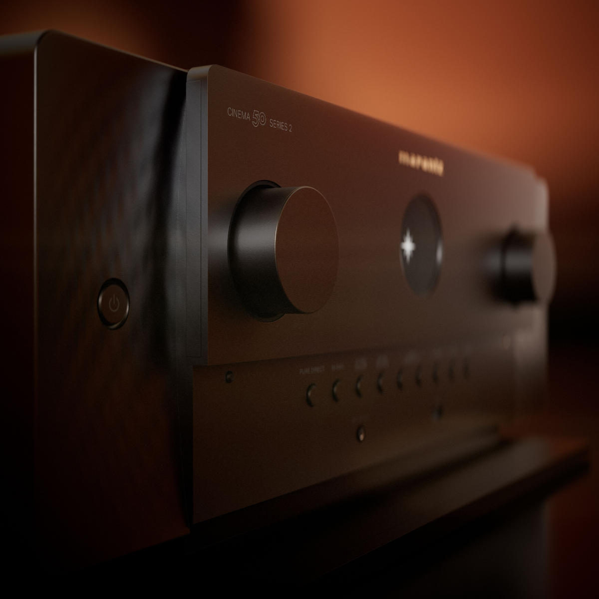 A close-up, angled view of a dark brown or black Marantz Cinema 50 Series 2 AV Receiver, showing its front control knobs and panel details against a warm, out-of-focus background.