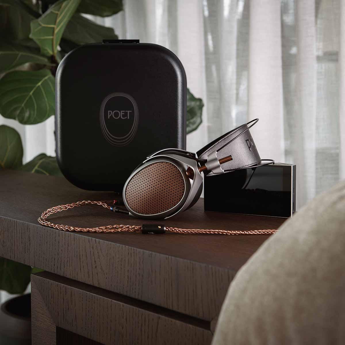 Meze Audio Poet High-Performance Planar-Magnetic Headphones lifestyle shot of headphones on table laying on side with cable attached and case in background