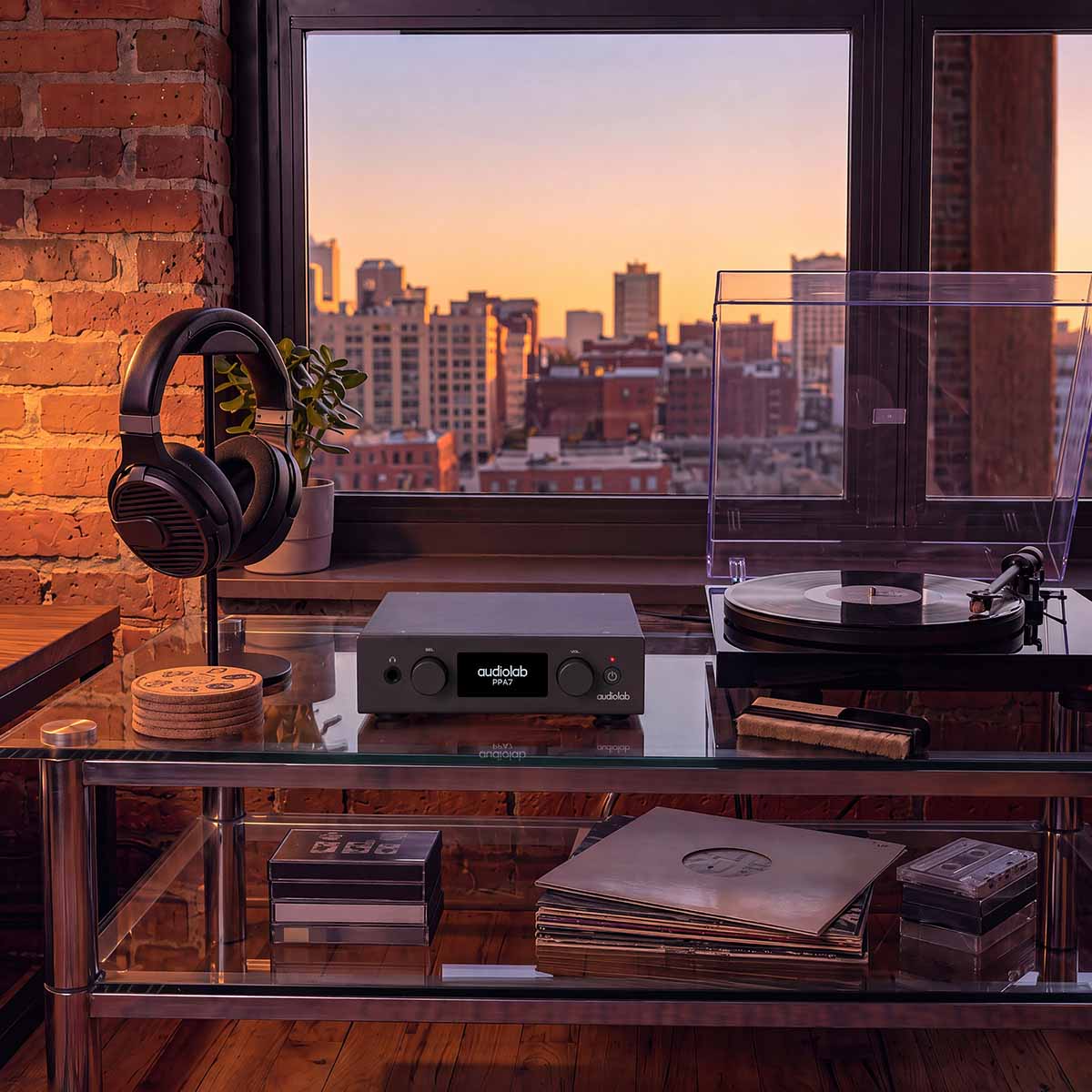 Audiolab PPA7 Phono Preamplifier - Black - lifestyle photo of unit on glass shelves to left of turntable and right of headphones on stand
