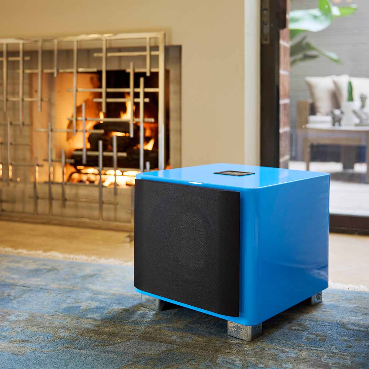 REL Acoustics T/9x SE Subwoofer Lifestyle photo of Blue subwoofer with grille angled left in front of fireplace