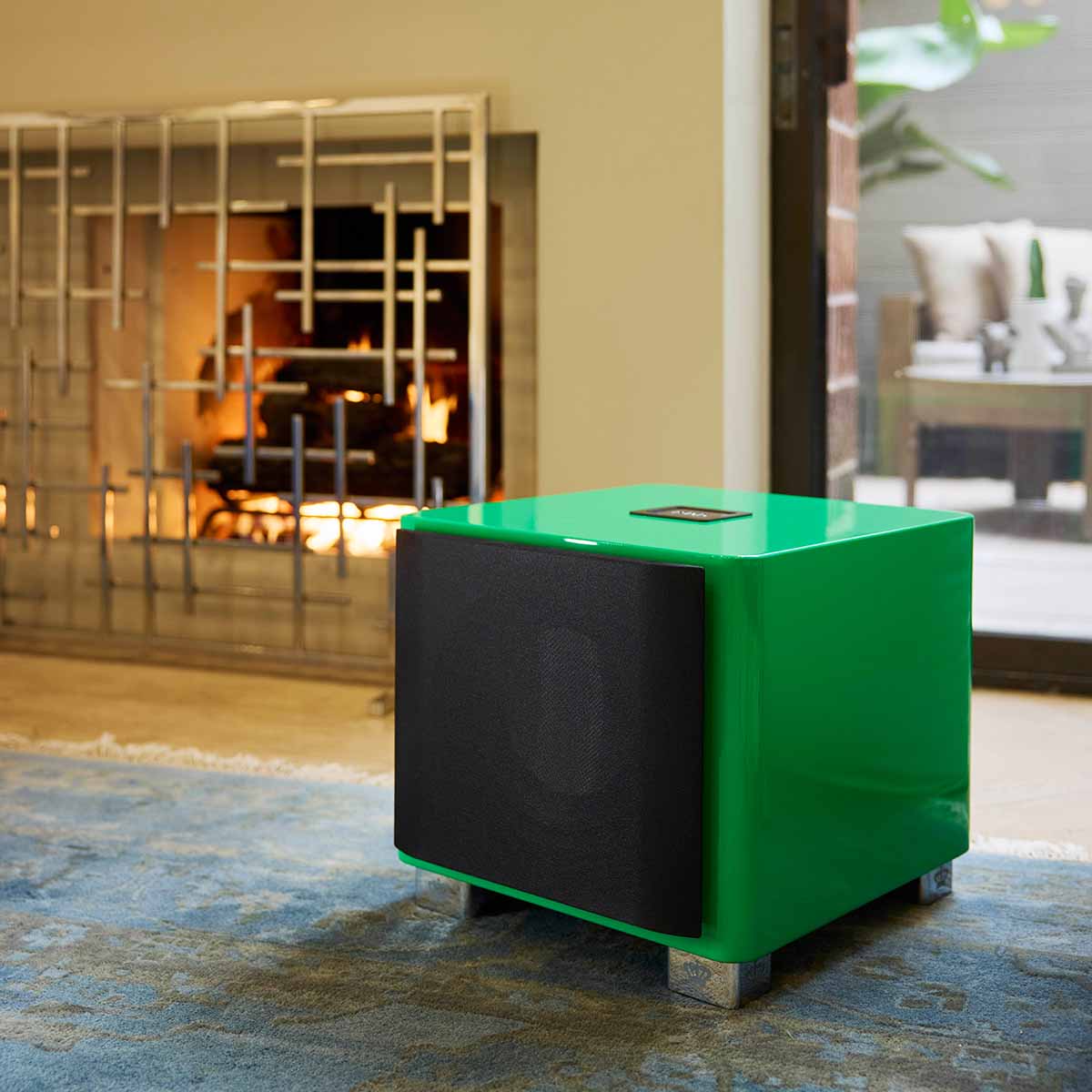 REL Acoustics T/9x SE Subwoofer Lifestyle photo of Green subwoofer with grille angled left in front of fireplace