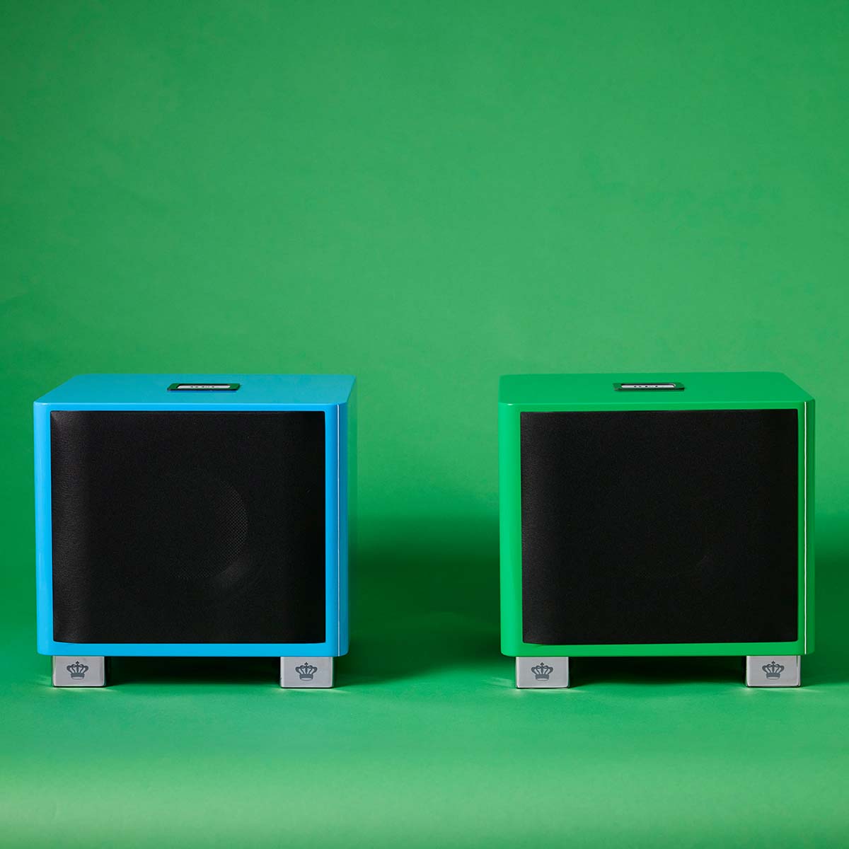 REL Acoustics T/9x SE Subwoofer Blue unit to left and Green unit to right front view with grilles on green background