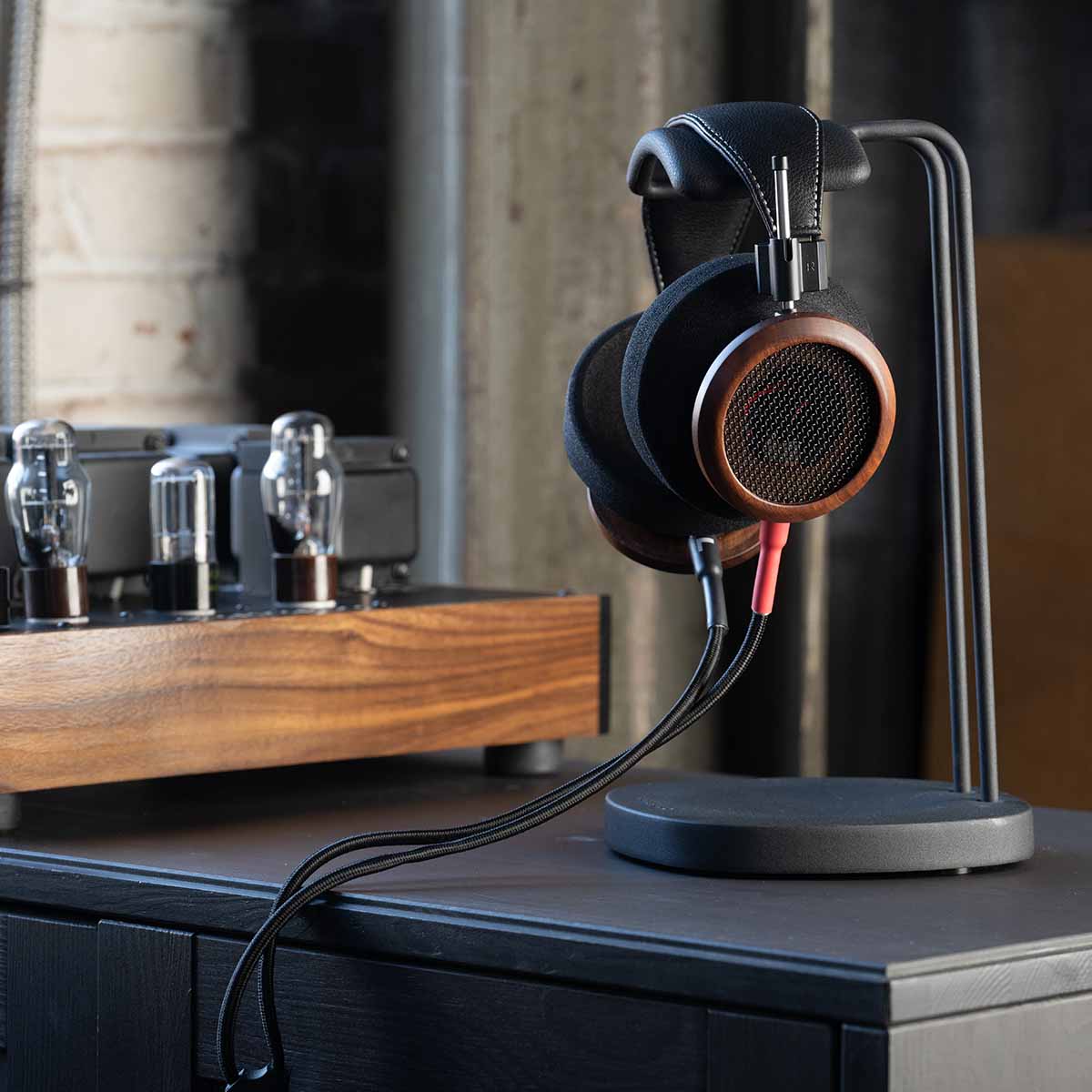Grado Signature S950 Headphone - lifestyle shot side view of right earphone on headphone stand next to headphone amp on cabinet