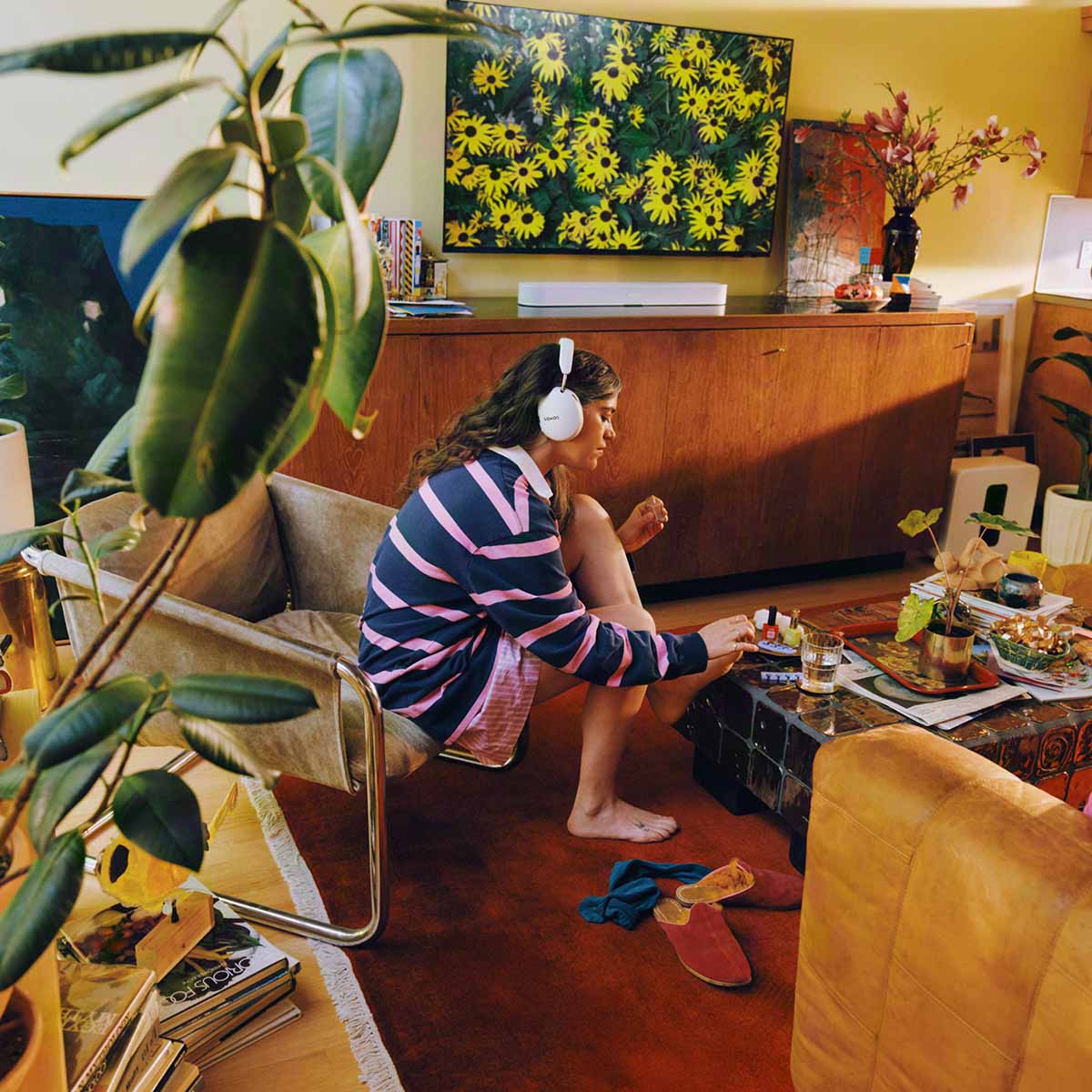 Sonos Ace Ultra Wireless Over-Ear Headphones - lifestyle photo of a woman wearing white headphones while painting her toenails