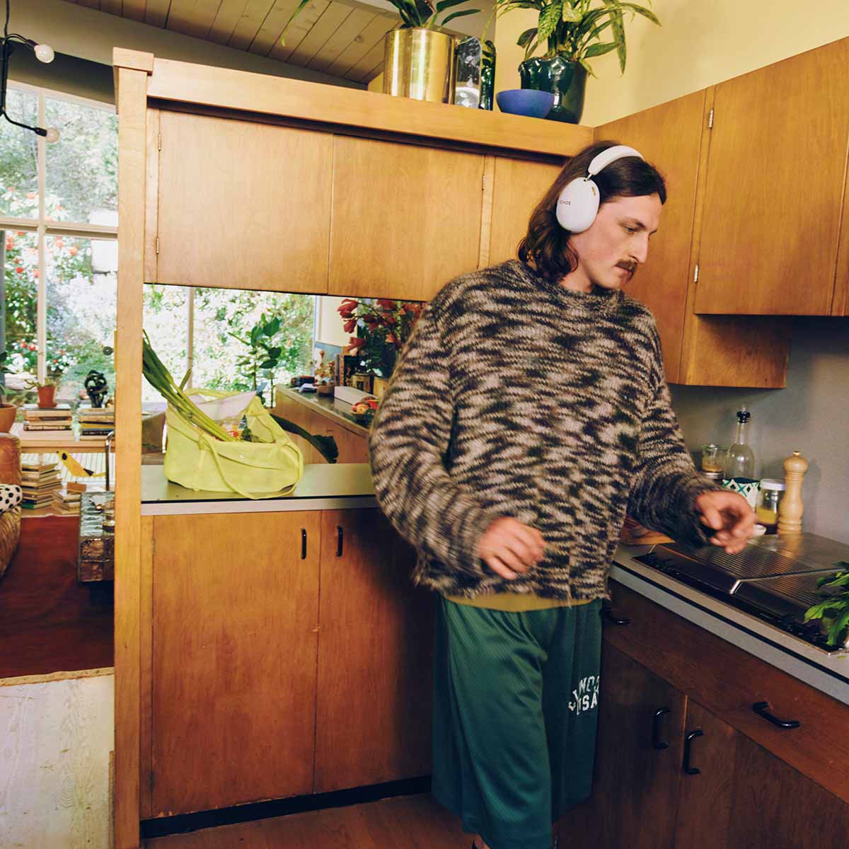 Sonos Ace Ultra Wireless Over-Ear Headphones - lifestyle photo of a man in a kitchen wearing white headphones