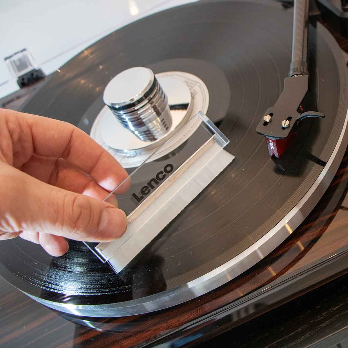 Lenco TTA-12IN1PRO Professional 12-in-1 Turntable Setup and Record Cleaning Kit record brush being held in front of turntable with record on platter
