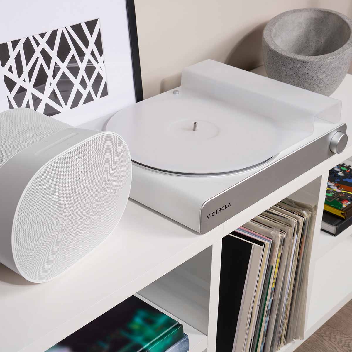 Victrola Stream Pearl Wi-Fi Streaming Turntable - white and silver - lifestyle shot front view angled right of unit on record cabinet with Sonos speaker to left